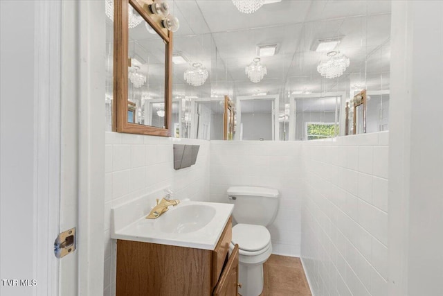 bathroom featuring tile walls, decorative backsplash, toilet, vanity, and tile patterned flooring