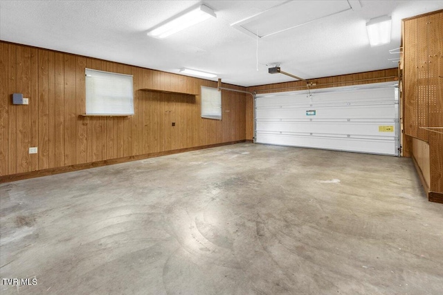 garage with wood walls, baseboards, and a garage door opener