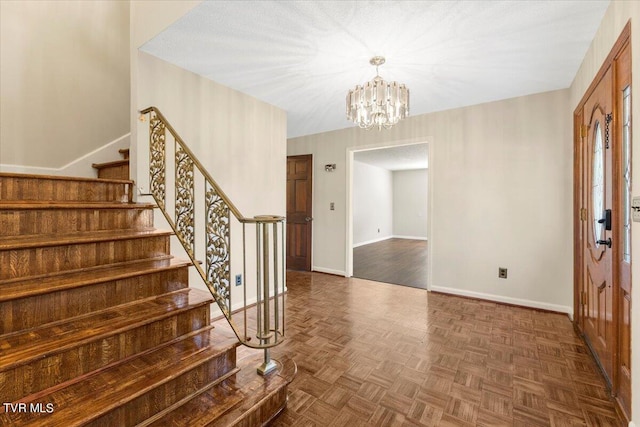 foyer entrance with stairs, a notable chandelier, and baseboards