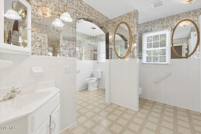 full bathroom featuring visible vents, wallpapered walls, toilet, wainscoting, and tile patterned floors