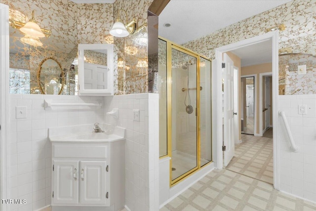 full bath with wallpapered walls, a wainscoted wall, tile patterned floors, a shower stall, and tile walls