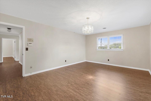 unfurnished room with baseboards, a textured ceiling, a chandelier, and wood finished floors