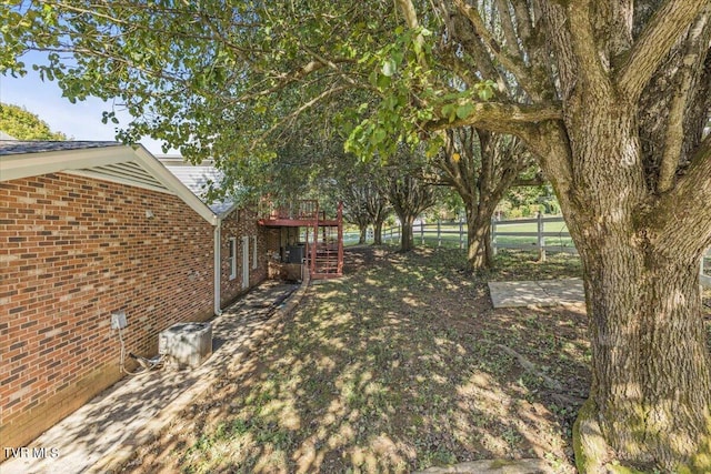 view of yard with fence, a wooden deck, and stairs