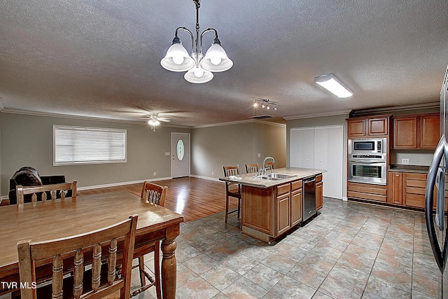 kitchen featuring crown molding, stainless steel appliances, open floor plan, a kitchen island with sink, and a sink