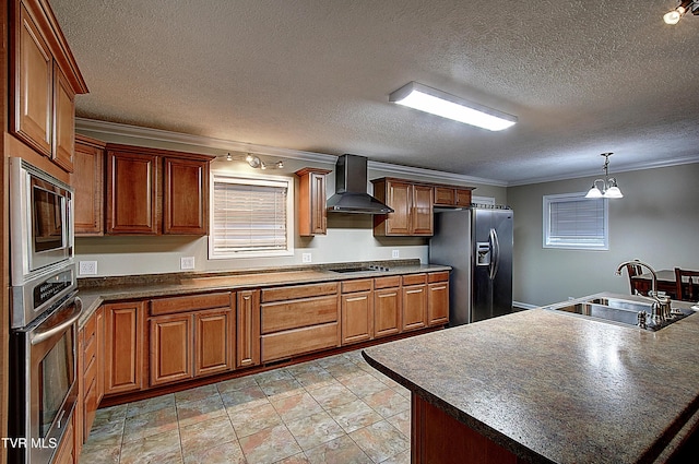 kitchen with stainless steel appliances, dark countertops, ornamental molding, a sink, and wall chimney range hood