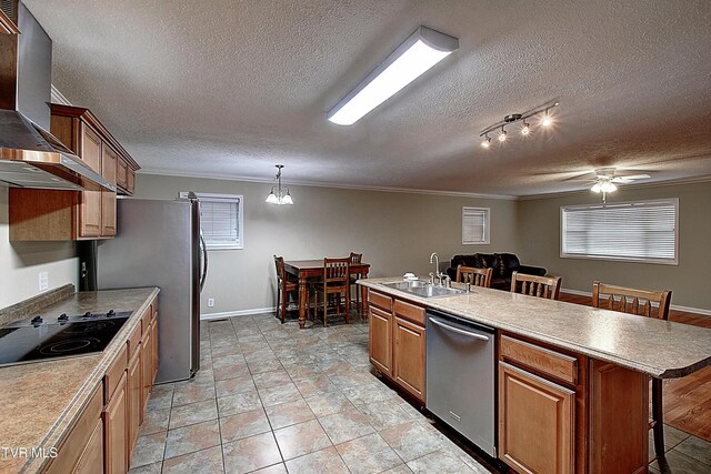 kitchen featuring appliances with stainless steel finishes, a breakfast bar, a textured ceiling, wall chimney range hood, and a sink