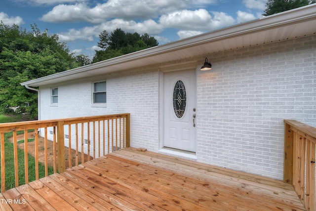 doorway to property featuring brick siding and a deck