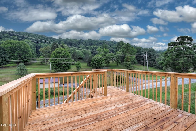 wooden terrace with a yard and a forest view