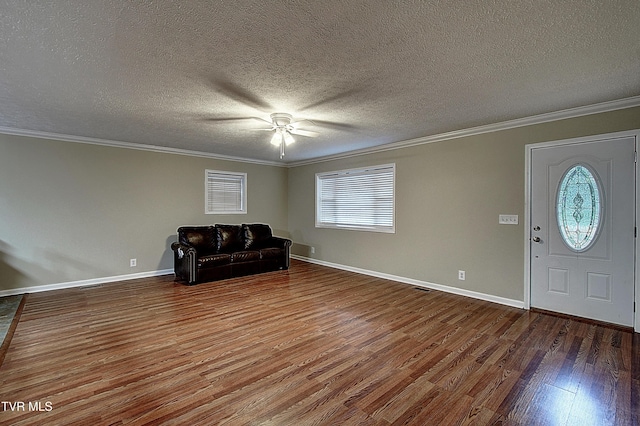 unfurnished room featuring baseboards, a textured ceiling, wood finished floors, and crown molding