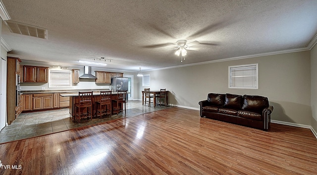 kitchen featuring visible vents, appliances with stainless steel finishes, open floor plan, wood finished floors, and wall chimney exhaust hood