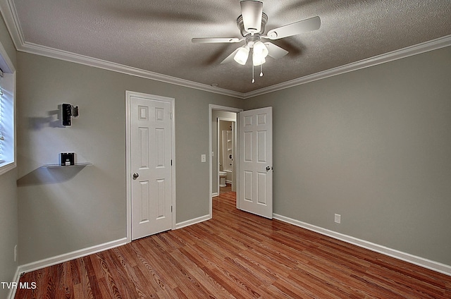 unfurnished bedroom with a textured ceiling, ornamental molding, and wood finished floors