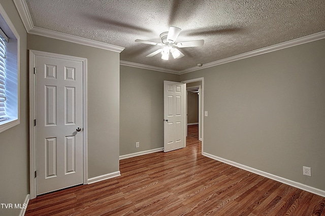 unfurnished bedroom with baseboards, a textured ceiling, ornamental molding, and wood finished floors