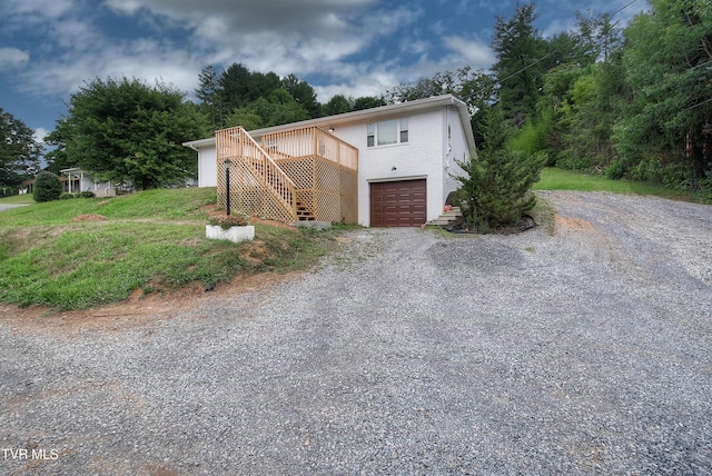 view of front facade with stairs, brick siding, gravel driveway, and a garage