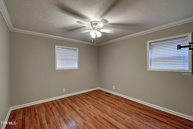 spare room featuring baseboards, visible vents, ceiling fan, wood finished floors, and crown molding