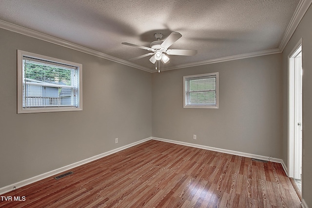 unfurnished room featuring baseboards, visible vents, ornamental molding, and wood finished floors