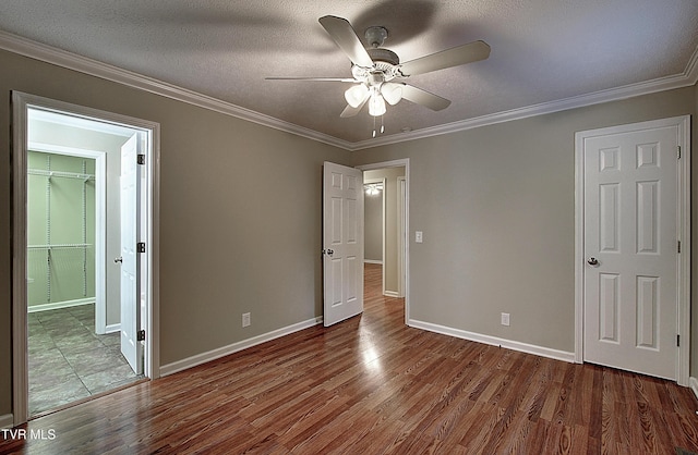 unfurnished bedroom with a textured ceiling, wood finished floors, and crown molding