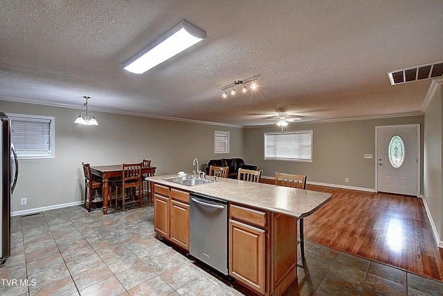 kitchen featuring visible vents, dishwasher, a kitchen breakfast bar, crown molding, and a sink