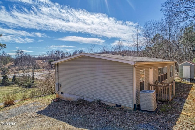 view of property exterior with crawl space, a storage unit, cooling unit, and an outbuilding