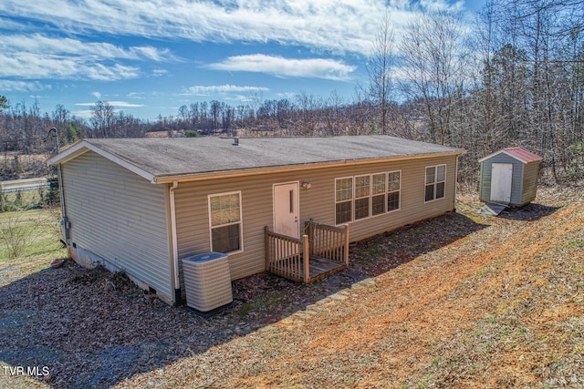 back of property with a storage unit, central AC unit, and an outbuilding