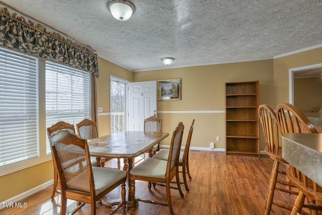 dining space with crown molding, baseboards, and wood finished floors