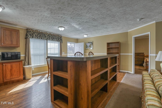 interior space featuring black microwave, a kitchen island, open shelves, dark countertops, and crown molding