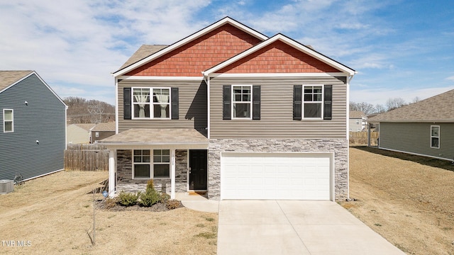 craftsman house featuring stone siding, an attached garage, fence, and driveway