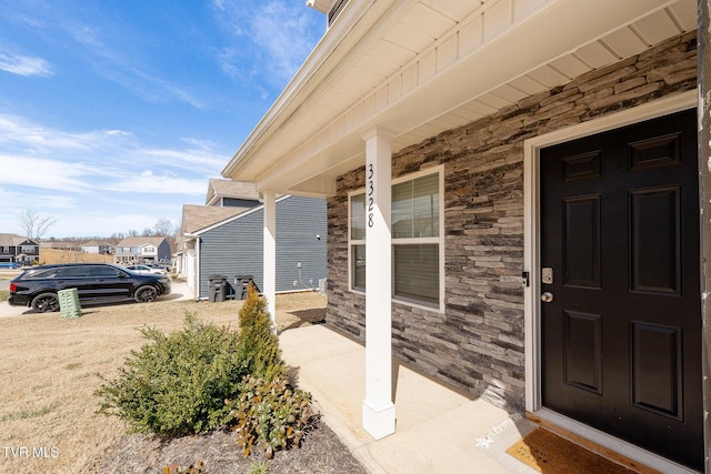 entrance to property with a residential view, stone siding, and covered porch