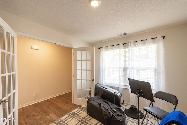 office area with baseboards, visible vents, wood finished floors, a textured ceiling, and french doors