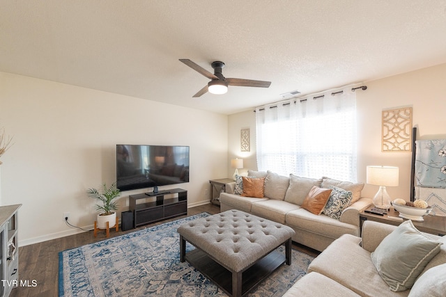 living area with dark wood-style floors, ceiling fan, baseboards, and a textured ceiling