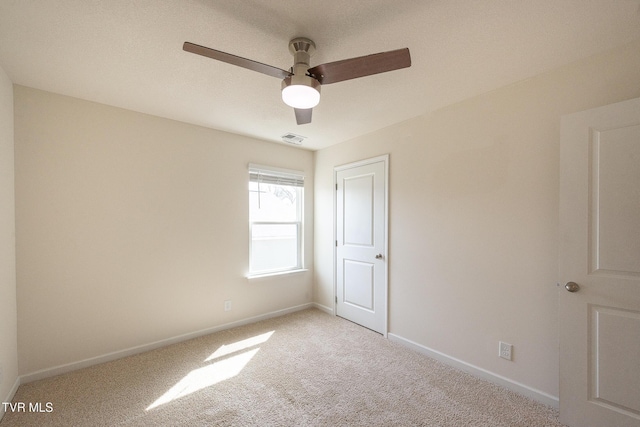 spare room with baseboards, a ceiling fan, visible vents, and light colored carpet