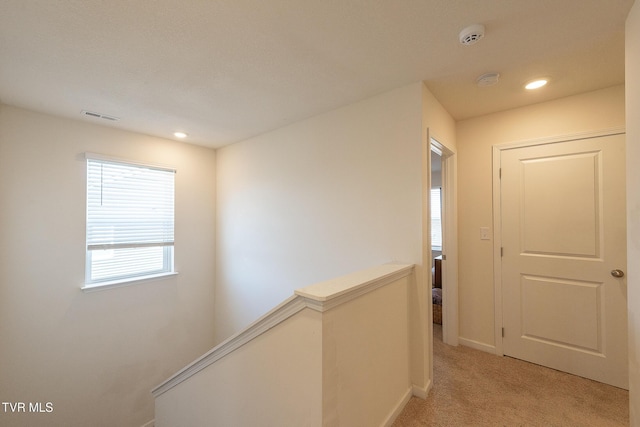 corridor with light carpet, visible vents, baseboards, an upstairs landing, and recessed lighting