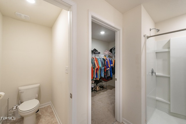 bathroom featuring a shower, a walk in closet, visible vents, toilet, and baseboards