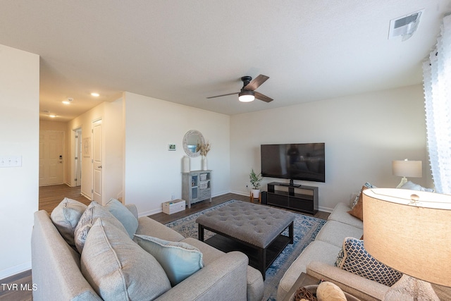 living area with a ceiling fan, wood finished floors, visible vents, and baseboards