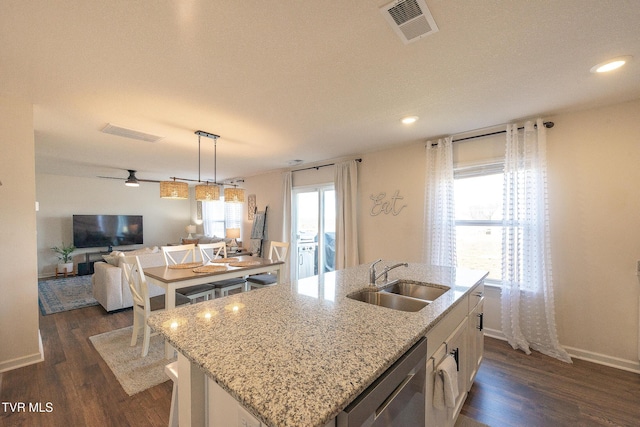 kitchen with visible vents, open floor plan, a kitchen island with sink, a sink, and dishwasher