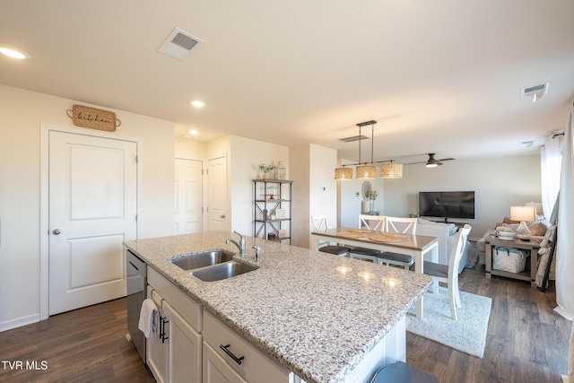 kitchen featuring a sink, visible vents, white cabinets, dark wood-style floors, and an island with sink