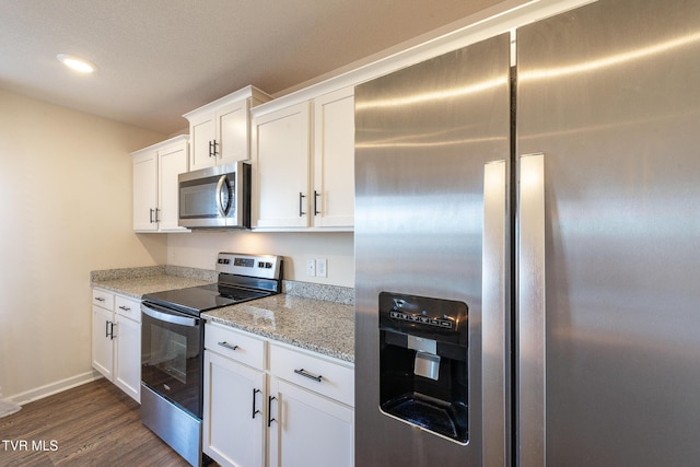 kitchen with light stone counters, dark wood-style floors, appliances with stainless steel finishes, white cabinets, and baseboards