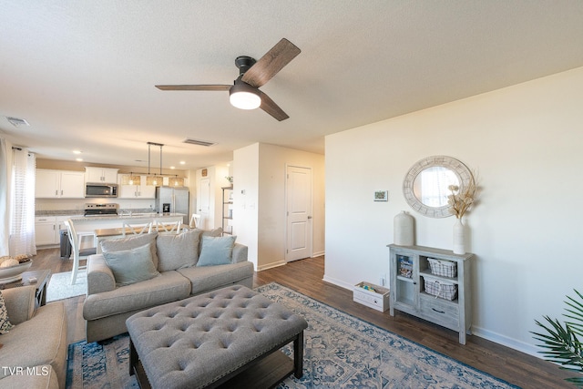 living area featuring baseboards, visible vents, and dark wood finished floors