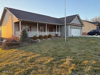 view of front of property featuring a garage, covered porch, and a front lawn