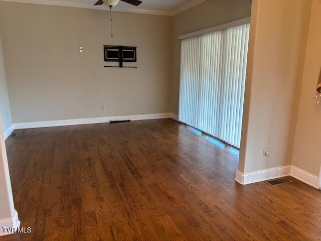 empty room with crown molding, baseboards, and wood finished floors