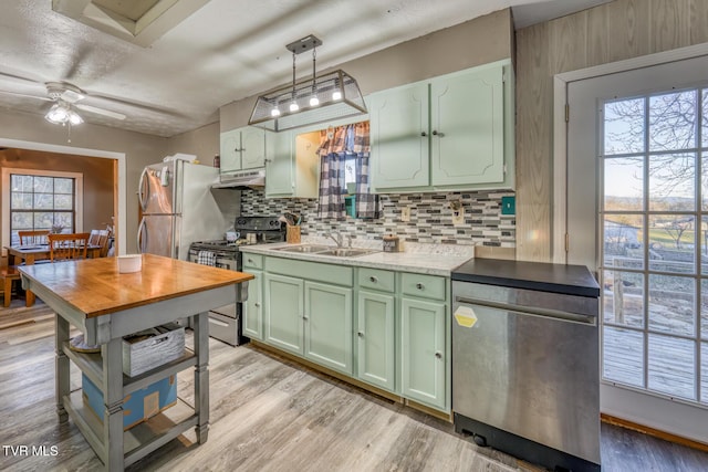 kitchen with stainless steel appliances, under cabinet range hood, a sink, and green cabinetry