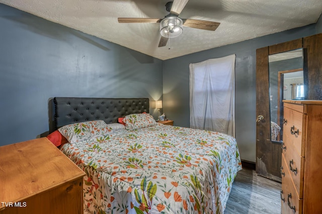 bedroom featuring a ceiling fan, a textured ceiling, and wood finished floors