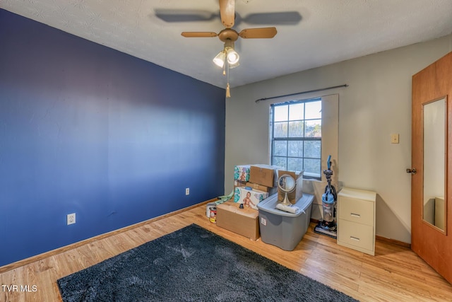 living area featuring a ceiling fan, baseboards, and wood finished floors