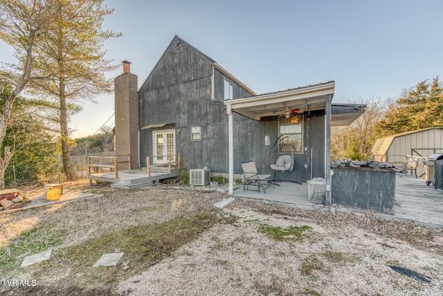 rear view of property with a deck, central air condition unit, a storage shed, an outdoor structure, and french doors