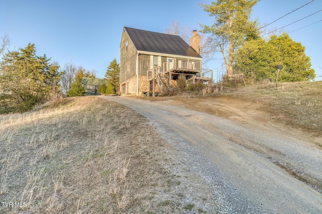 view of front of property featuring a deck, driveway, and a chimney