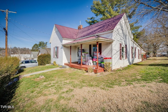 view of front of house with covered porch, metal roof, a chimney, and a front lawn