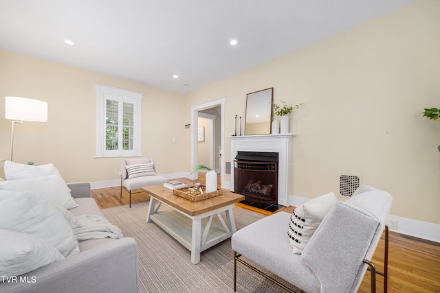 living area featuring recessed lighting, light wood-type flooring, a fireplace with flush hearth, and baseboards