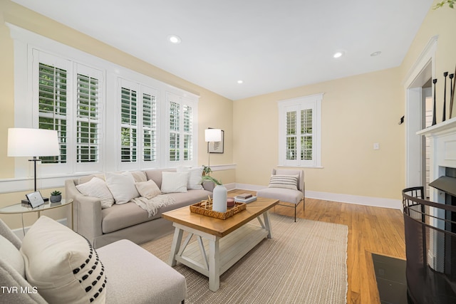 living area with light wood finished floors, a fireplace with flush hearth, baseboards, and a wealth of natural light