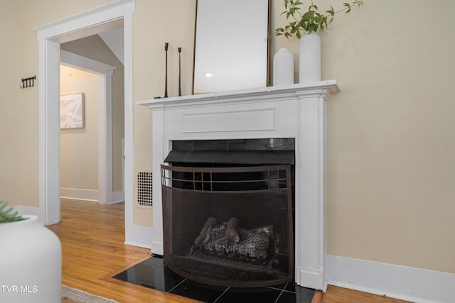 room details with wood finished floors, a fireplace with flush hearth, and baseboards