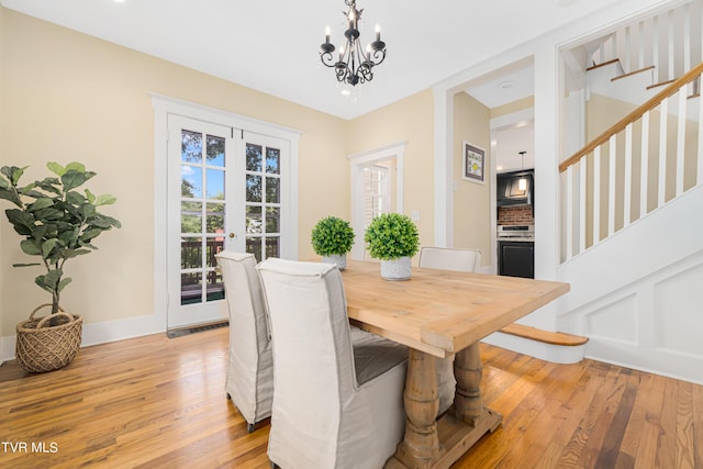 dining space featuring baseboards, light wood-style flooring, an inviting chandelier, and stairs