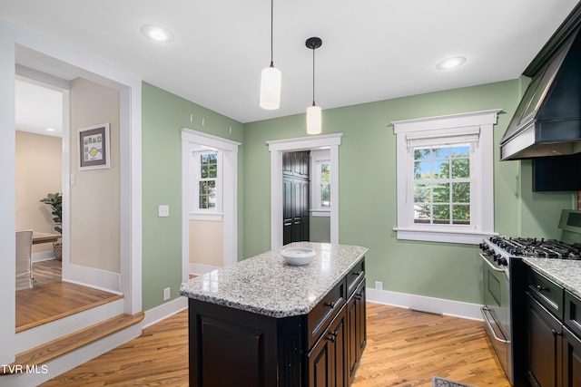 kitchen featuring light wood finished floors, premium range hood, stainless steel gas range, and a wealth of natural light